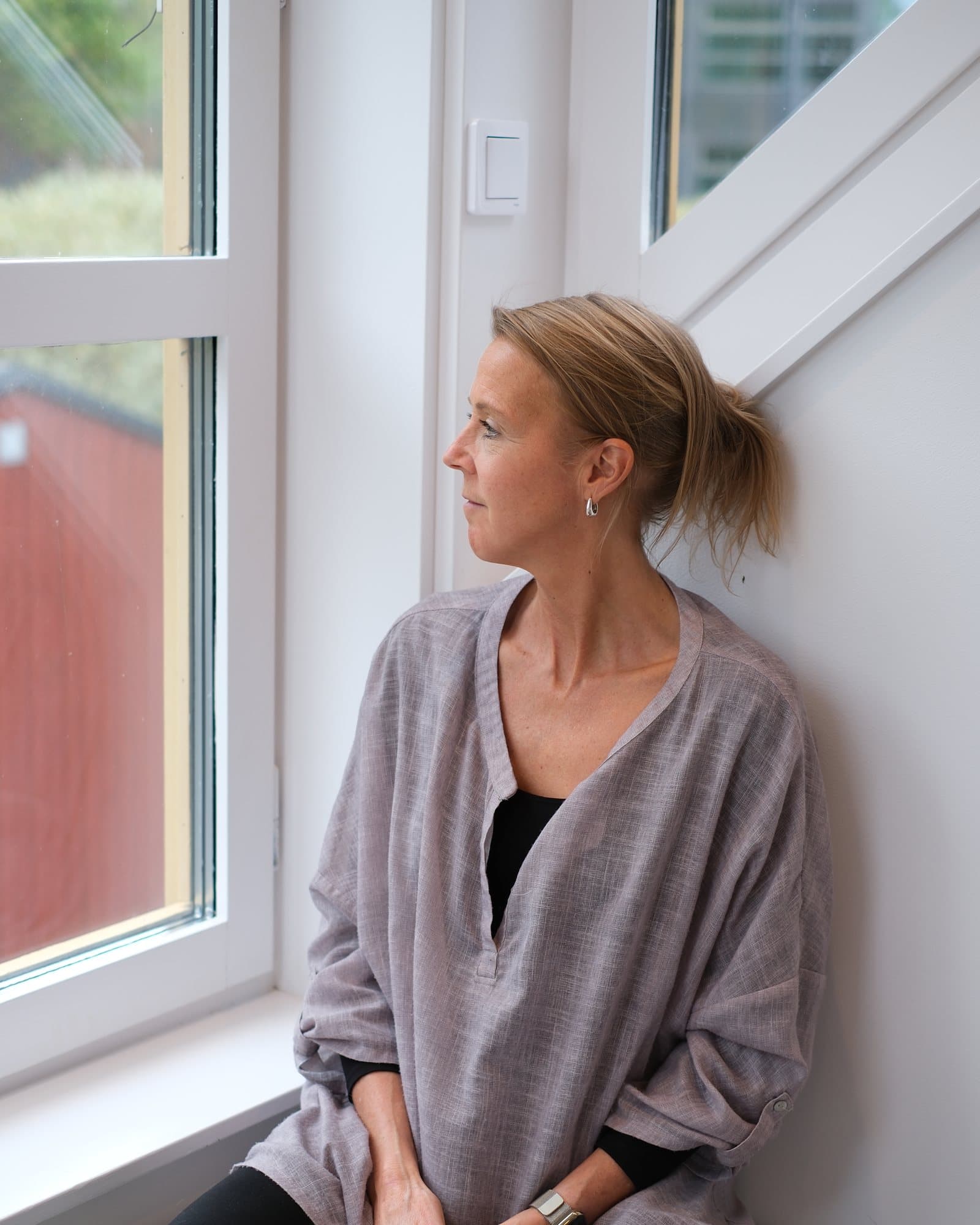 Pia sitter vid ett fönster och tittar ut